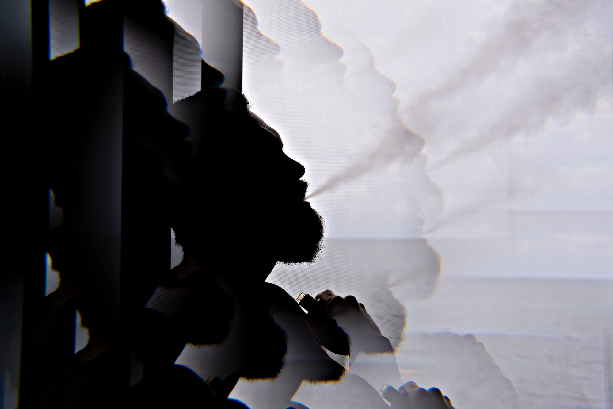 Silhouette of bearded smoking man vaping vape with kaleidoscope effect