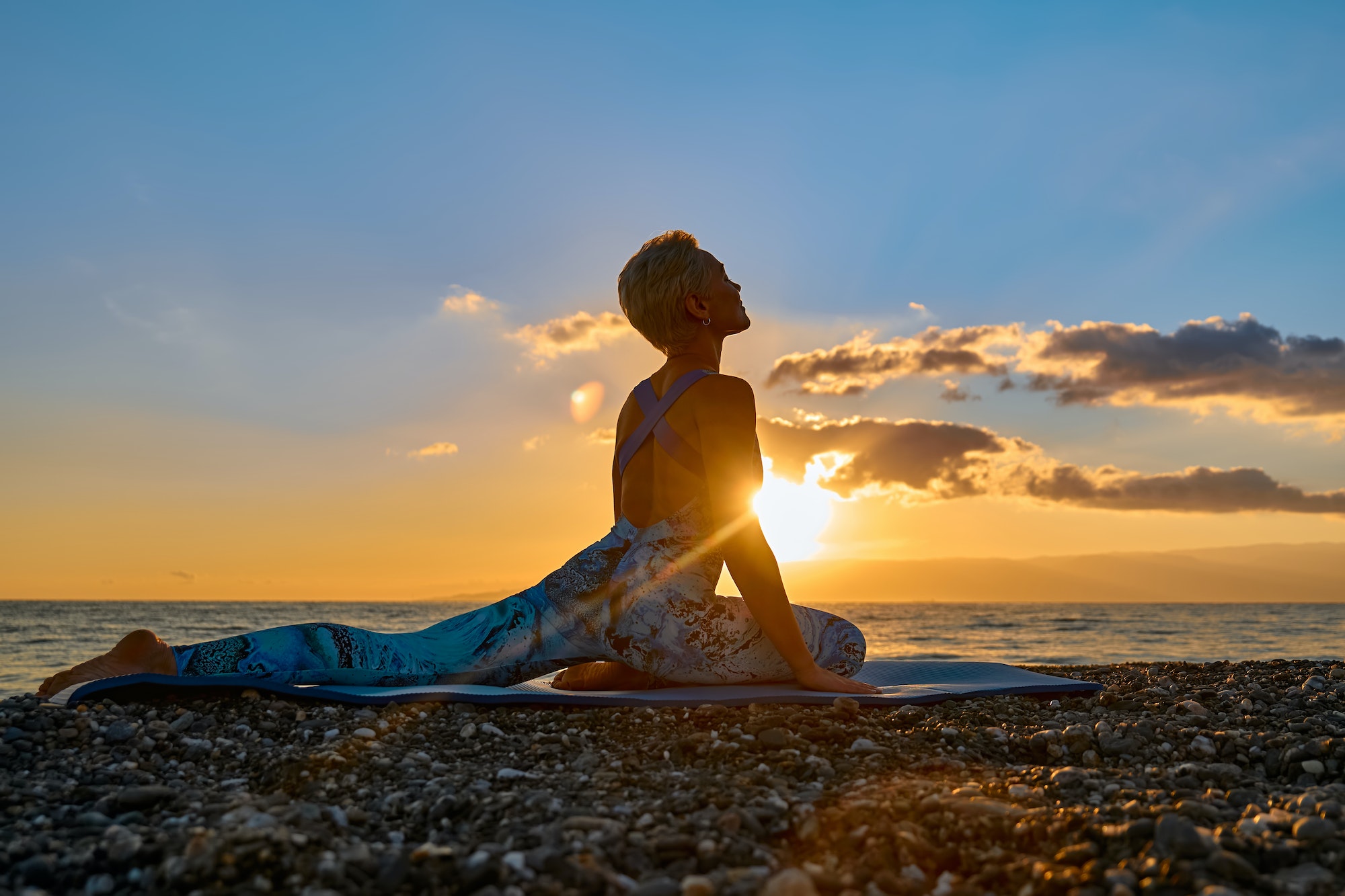 Young woman practicing yoga on the beach at sunrise. Harmony, wellbeing, meditation.